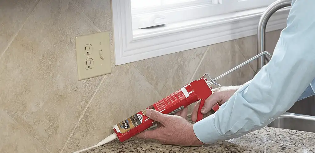 Handyman applying caulk along a kitchen backsplash and countertop seam in Louisville, KY