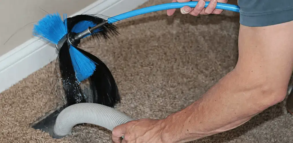Dryer vent cleaning technician brushing lint from a vent line in Louisville, KY