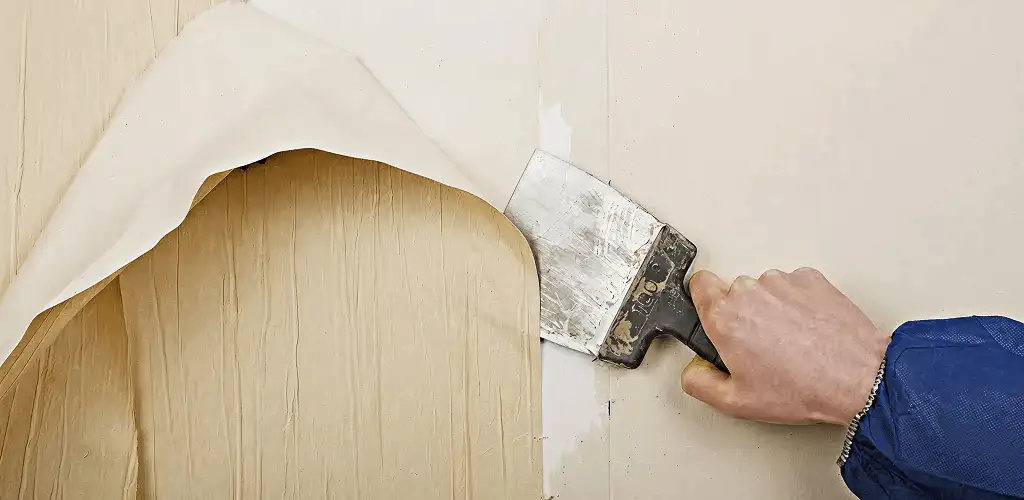Handyman removing wallpaper with a scraper for wall preparation in Louisville, KY