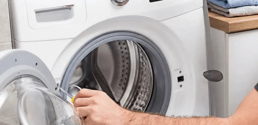 Handyman repairing a front-load washing machine and inspecting the drum in Louisville, KY