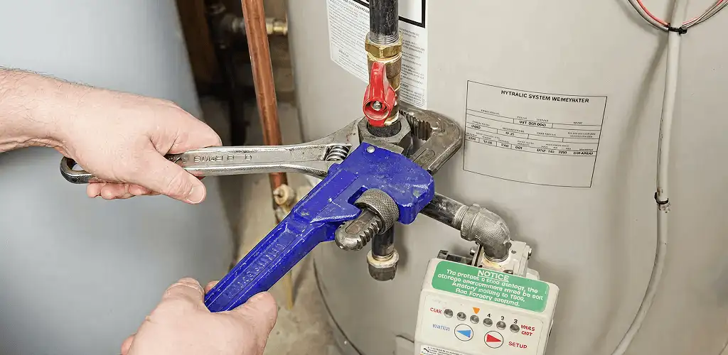 Water heater repair technician tightening the shutoff valve and supply line in Louisville, KY